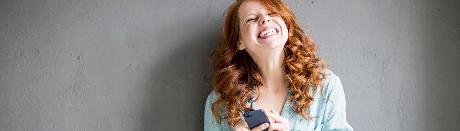 Frau mit Handy in der Hand freut sich