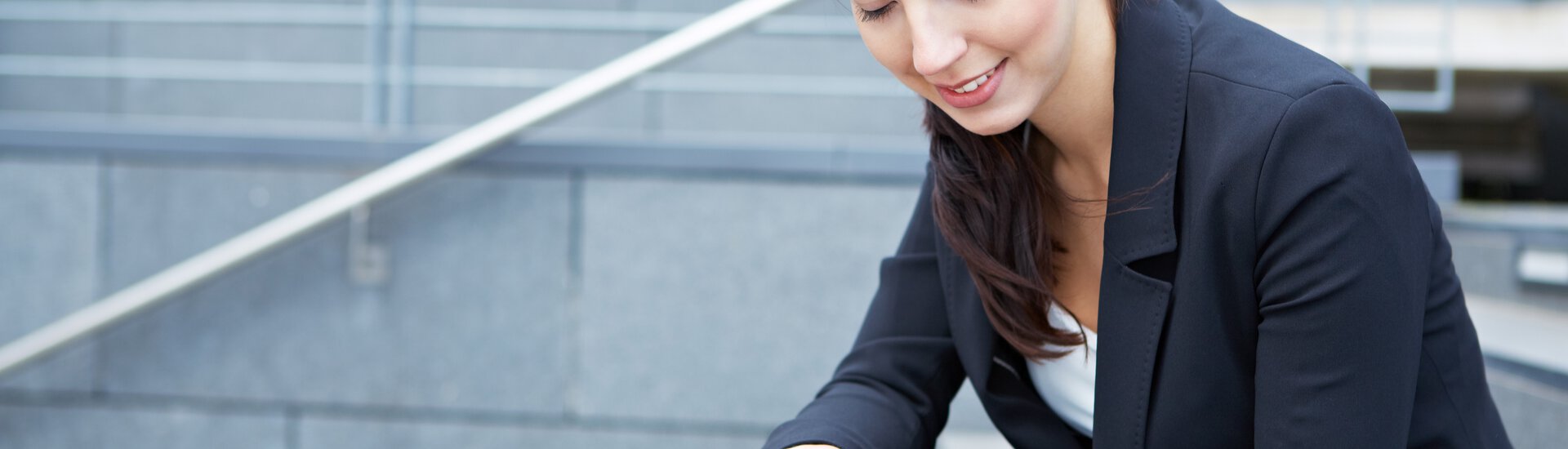 Frau sitzt draußen auf Treppen mit einem Tablet in der Handy