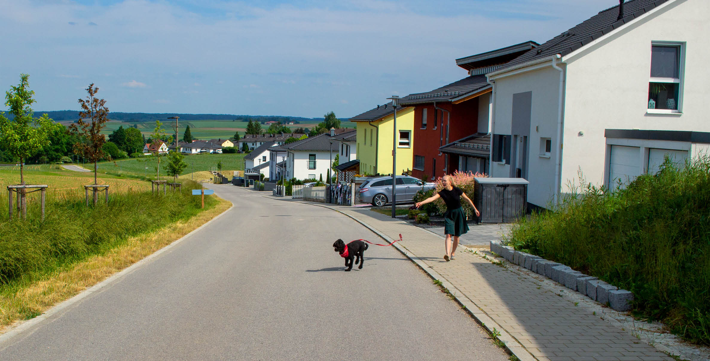 Frau mit Hund an der Leine in Wohngebiet