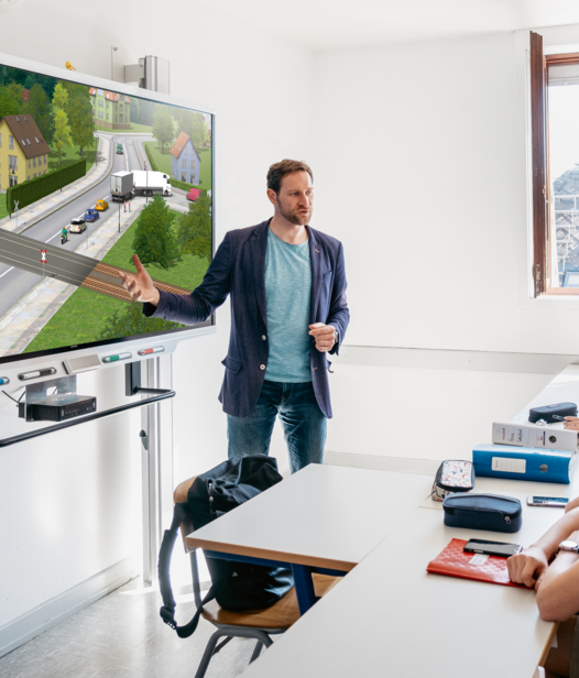 Lehrer steht vor großem Smartboard und unterrichtet mit PC Professional