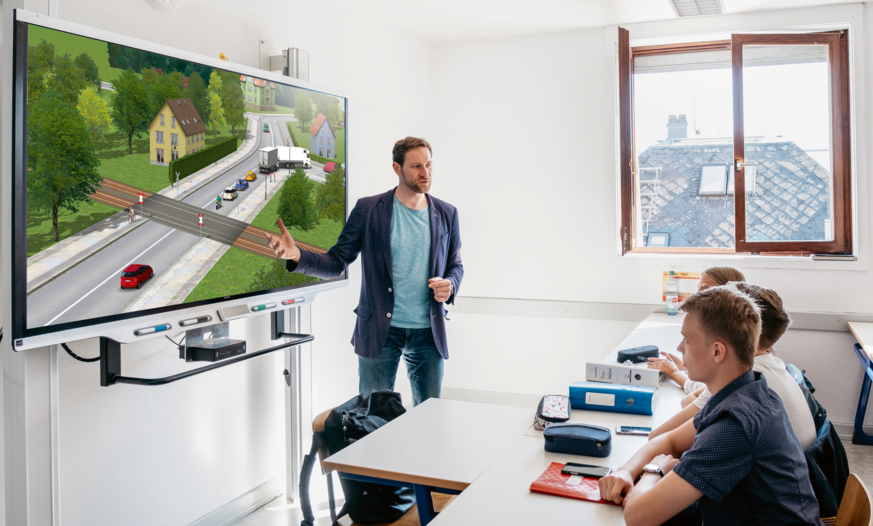 PC Professional Smartboard Lehrer steht vor großem Smartboard und unterrichtet mit PC Professional
