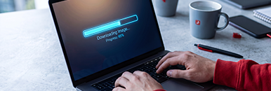 Laptop auf Schreibtisch mit Progressbar "Bilddownload"